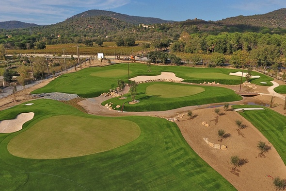 Custom putting green turf installation with contoured synthetic greens, sand bunkers, and surrounding fairway turf set against scenic mountain views.