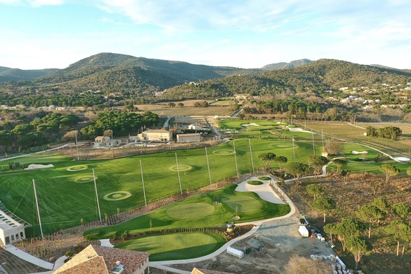 Expansive putting green turf installation with multiple synthetic practice greens, target areas, and sand bunkers set within a scenic golf training facility.