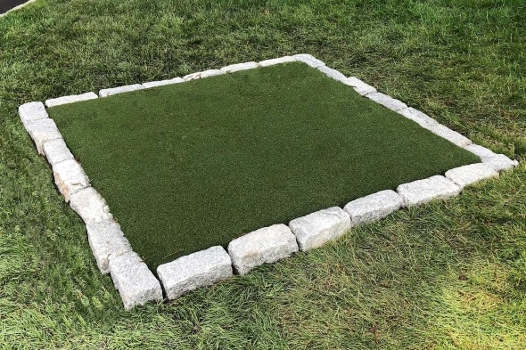 Tee box made of synthetic grass surrounded by stone border